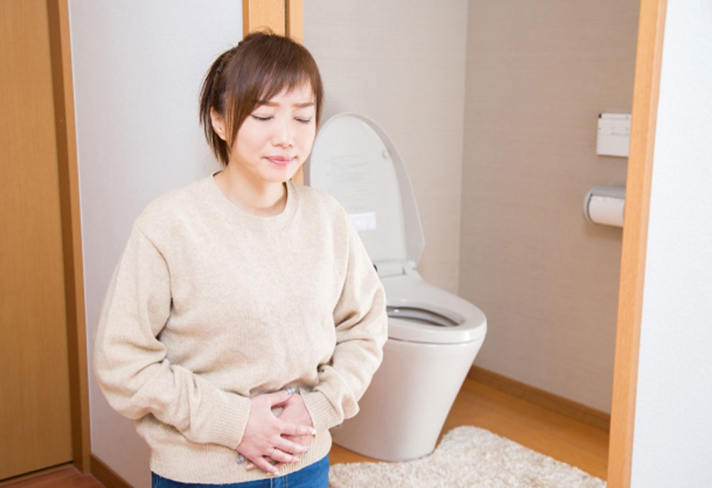 トイレでお腹を押さえている女性